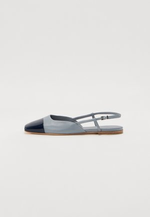 Mocassins à talon ouvert en cuir bleu clair avec un bout en cuir verni bleu marine, présentant un design à deux brides et une semelle extérieure beige.