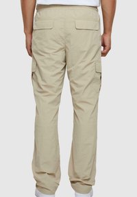 Beige cargobroek met een relaxte pasvorm, voorzien van twee achterzakken en zijzakken, gemaakt van lichtgewicht, gestructureerde stof.