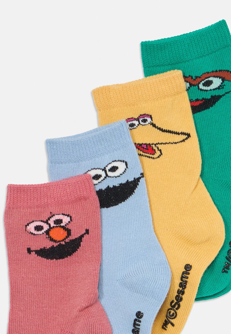 Quatre paires de chaussettes en coton avec des visages de personnages de dessins animés. Couleurs : rose, bleu, jaune et vert. Chaque paire affiche des designs faciaux détaillés.