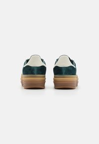 Zapatillas de ante verde con acentos blancos y suela de goma, que cuentan con un diseño de corte bajo y un collar acolchado para mayor comodidad.