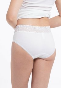 Weiße Baumwollunterhosen mit einem Blumen-Spitzenbund, nahtlosen Kanten und weicher Textur. Die Rückansicht hebt das Design des Bundes hervor.