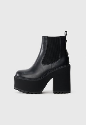 Czarny skórzany botek za kostkę z elastycznymi panelami po bokach, grubą platformą i masywnym obcasem z bieżnikowaną podeszwą zapewniającą przyczepność.