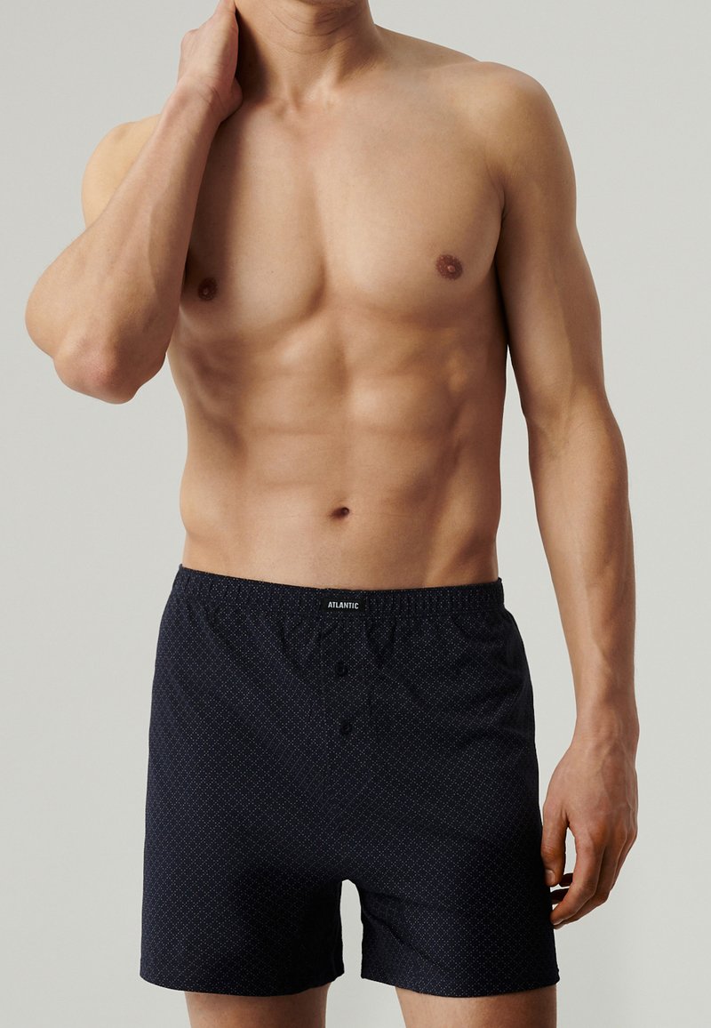 Granatowe bokserki wykonane z miękkiej tkaniny, z całkowitym wzorem w romby, elastycznym pasem i detalami w postaci guzika z przodu.