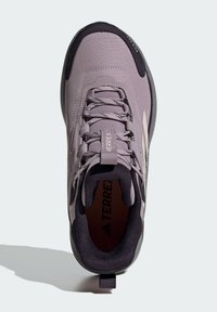 Fialové lehké tenisky s texturovaným svrškem, šněrováním a kontrastní černou podrážkou. Obsahují poutko na patě pro snadné obutí.