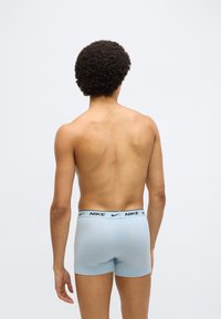 Φωτεινά γαλάζια μπόξερ με λογότυπο Nike σε μαύρο χρώμα στη λαστιχένια μέση. Το ύφασμα φαίνεται μαλακό και εφαρμοστό, κατάλληλο για άνεση και υποστήριξη.