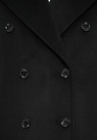 Μαύρο μάλλινο παλτό με διπλό κούμπωμα, διαθέτοντας έξι στρογγυλά μαύρα κουμπιά και γιακά με σχισμές. Μαλακή υφή και προσαρμοσμένη εφαρμογή.