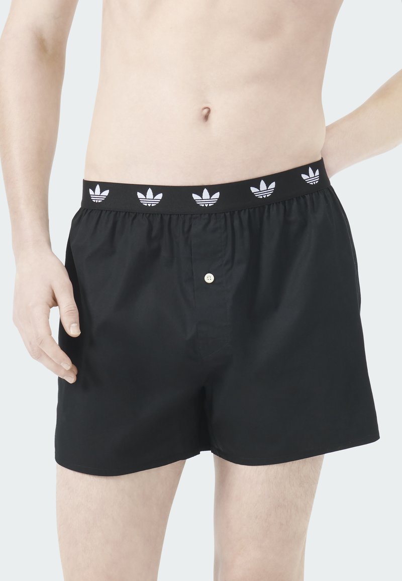 Schwarze Boxershorts mit elastischem Bund, der wiederholt das weiße Adidas-Trefoil-Logo zeigt, Einzelknopfverschluss und weichem Baumwollmaterial.