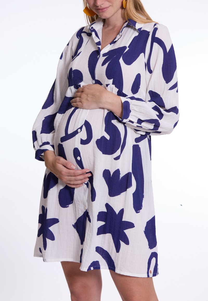 Langärmliges Kleid aus leichtem Stoff mit navyblauen abstrakten Mustern. Verfügt über einen Knopfverschluss vorne und eine taillierte Empire-Taille, ausgelegt für die Schwangerschaft.