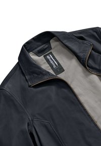 Giubbotto di pelle nera con una texture liscia, dotato di un colletto ripiegato, rivestimento beige e una cerniera con un accento in tonalità rame.