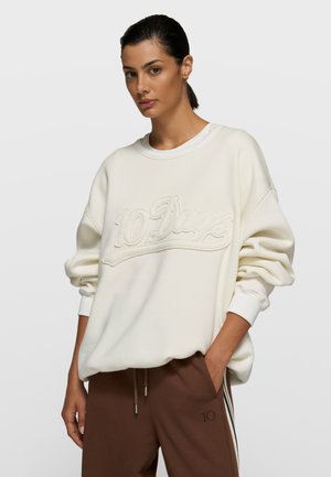 Off-white sweatshirt with oversized fit, ribbed neckline, and embroidered "10 Days" logo. Soft material, featuring dropped shoulders and cuffed sleeves.