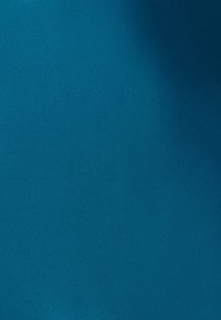 Usmívající se žena jezdí na černém bicyklu s košíky v městském parku za slunečného dne.