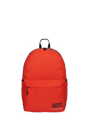 Rode rugzak van een gestructureerd canvasmateriaal, met een afgeronde bovenkant, een voorvak met ritssluiting en zwarte merkopdruk. Voorzien van zwarte accenten aan de riemen en metalen onderdelen.