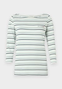 Λευκό πουκάμισο με μακριά μανίκια, με οριζόντιες ρίγες σε ανοιχτό μπλε και μαύρο, σχήμα μποτ, και το μήνυμα "η αγάπη είναι τα πάντα" κεντημένο με μια μικρή κόκκινη καρδιά.