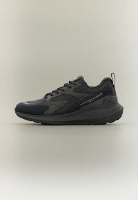 Svart atletisk sneaker med mesh- og syntetisk overdel, teksturerte detaljer og en polstret såle med et fremtredende mønster.