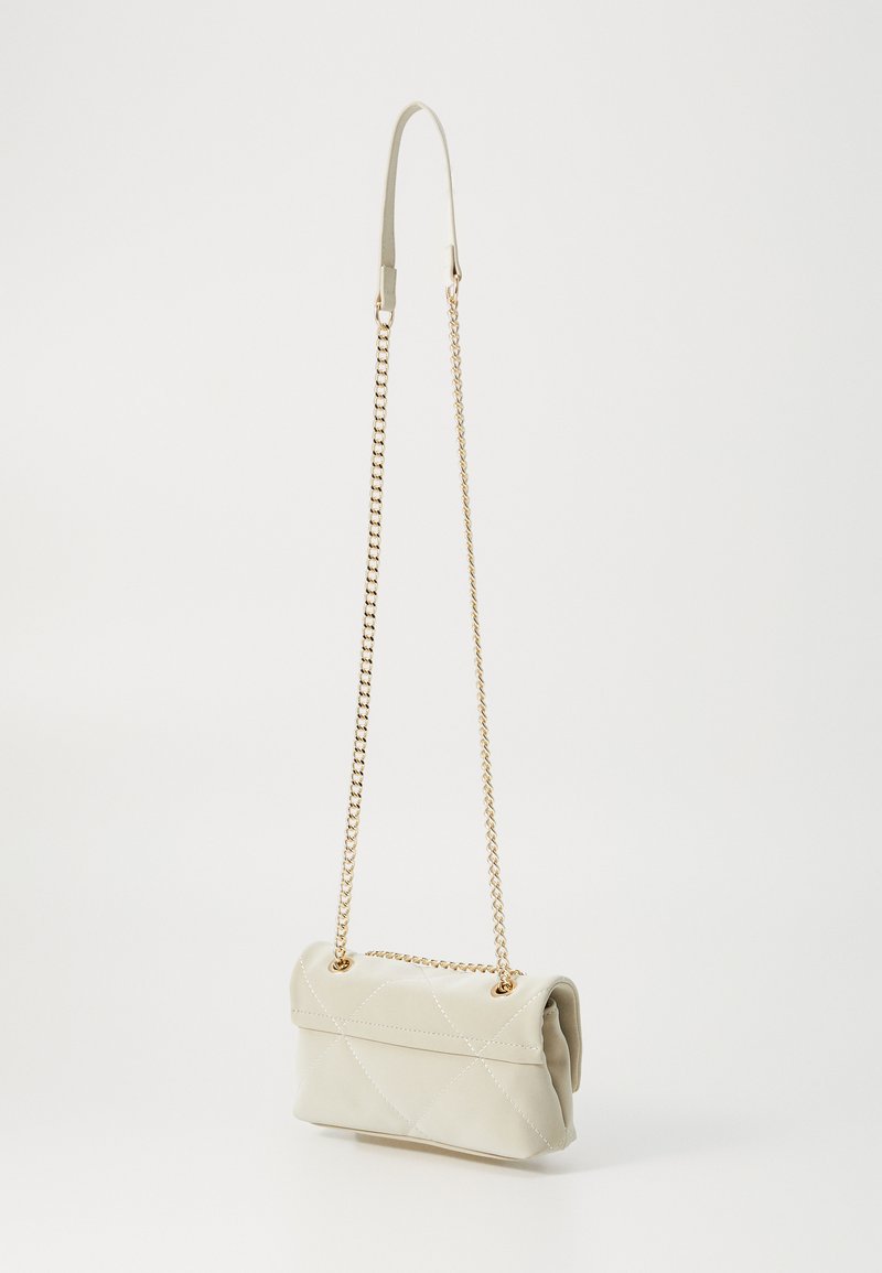 Sac à main en cuir matelassé beige doux avec une bandoulière en chaîne dorée, présentant un design à rabat et des détails de couture subtils.