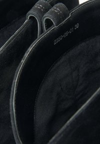 Černé semišové boty s hladkým povrchem, s prošívanými okraji, zaoblenými otvory a embosovanými detaily produktu uvnitř.