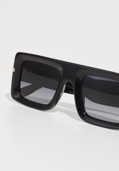 Black square sunglasses with gradient lenses, thick plastic frames, and a small gold accent on the side. Elegant design with a modern aesthetic.