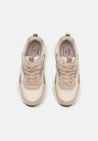 Beżowe i kremowe siateczkowe sneakersy z teksturowanymi nakładkami, okrągłym czubkiem, tonowymi sznurowadłami i gumową podeszwą. Logo widoczne wewnątrz buta.