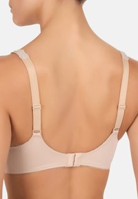 Beige bh med glat stof, justerbare stropper og delikate lace-detaljer langs stropkanterne. Krogelukning bagpå.