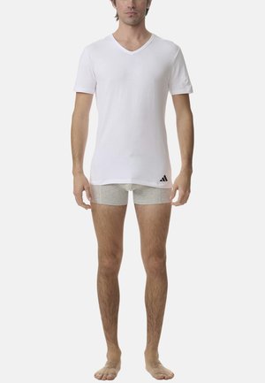 T-shirt blanc à col en V en coton, en tissu léger. Short gris en dessous. Logo Adidas en noir sur le côté gauche.