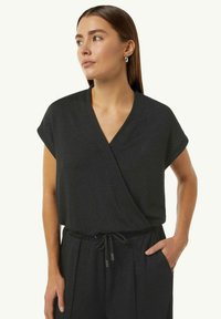 Black, short-sleeve wrap top with a v-neck design, featuring a subtle shimmer and an elastic waistband, paired with pants.