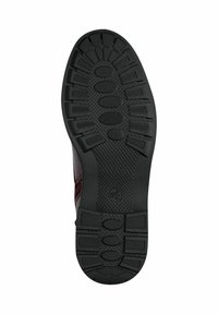Semelle de chaussure en caoutchouc avec une surface texturée ; présente des motifs circulaires et ovales pour l'adhérence ; principalement noire avec de légers accents de design.