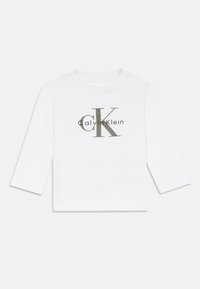 Valge pika varrukaga särk ümmarguse kaeluse ja nööbiga detailiga. Esiplaanil on hall "CK" logo ja "Calvin Klein" tekst.