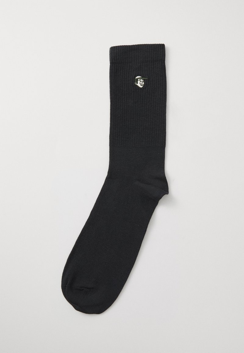 Μαύρες ριχτές κάλτσες με υφή, διαθέτοντας ένα μικρό κεντημένο λογότυπο σε λευκό και πράσινο κοντά στον γιακά.