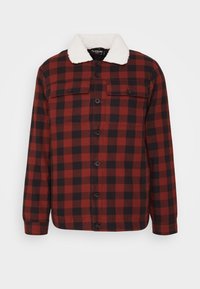 Camisa de botão em padrão xadrez vermelho e preto com collor de sherpa branco, dois bolsos no peito e mangas longas. Tecido de algodão com uma textura suave.
