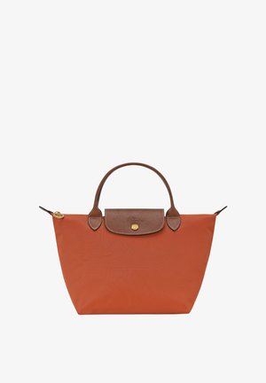 Orange nylon handbag with brown leather accents, two handles, a front pocket, and a snap closure. Smooth texture, minimalist design.