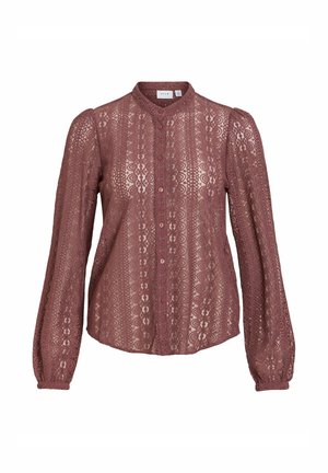 Blouse en dentelle mauve à manches longues avec motifs floraux, boutonnée sur le devant, col haut et épaules légèrement bouffantes.