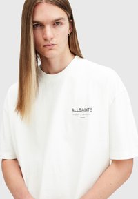 White cotton t-shirt with a relaxed fit, featuring a subtle "ALLSAINTS" logo in gray on the left chest area.