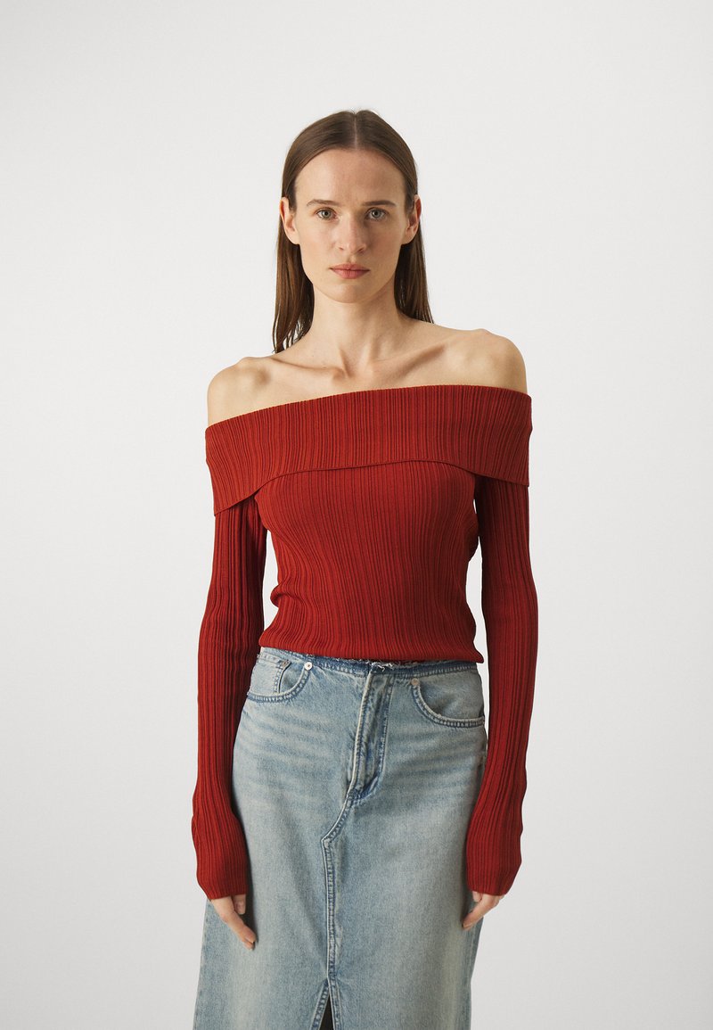 Red off-the-shoulder ribbed top with long sleeves, paired with a light blue denim skirt featuring a front slit and standard pockets.