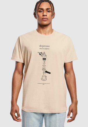 Beige medvilninis marškinėliai su iliustracija ir tekstu „depresso“, kavos tema iliustruotais grafika, trumpomis rankovėmis ir laisvu siluetu.