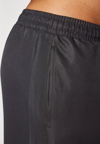 Black athletic shorts featuring a textured fabric, elastic waistband, and side pockets. Smooth finish with a lightweight design.