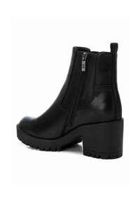 Botas negras hasta el tobillo de cuero liso, con cremallera lateral, punta redondeada y un tacón grueso con suela texturizada para mayor agarre.
