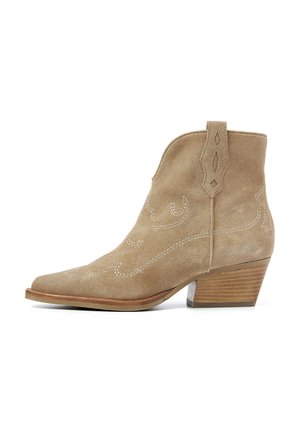 Beige suede ankle boot with pointed toe, decorative stitching, pull tab, and a stacked wooden heel. Texture appears soft and smooth.