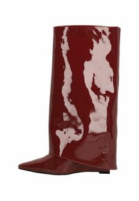 Botte en cuir verni rouge foncé brillant, montante jusqu'au genou, avec un bout pointu et un talon plat bas, présentée de côté sur fond blanc.