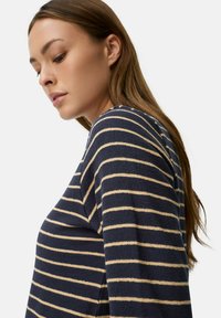 Marineblå og cremefarvet stribet sweater med rund halsudskæring og lange ærmer, der har et blødt, tekstureret stof og en afslappet pasform.