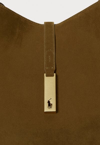 Smeđa torba od antilopa s pravokutnom oznakom zlatne boje s utisnutim logotipom, pričvršćena pomoću odgovarajuće petlje od antilopa.