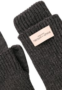 Graue gestrickte fingerlose Handschuhe mit einem gerippten Muster und einem beigen Etikett, das Marken- und Pflegeinformationen enthält.