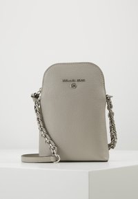Liten grå pebblad läder Michael Kors crossbody-väska med silverkedjestraps och logotyp på framsidan, placerad på en vit yta.