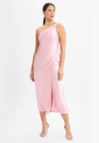 Eén-schouder roze satijnen jurk met gedrapeerde details, aansluitende silhouet en een hoge split tot boven de dij. G gedragen met strappy zilveren hakken.