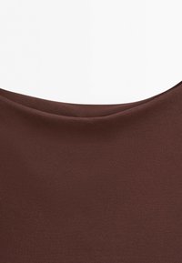 Close-up of a brown fabric with a smooth, slightly curved seam or edge on a white background.