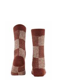 Stricksocken im rost- und cremefarbenen karierten Muster, mit einer strukturierten Oberfläche und kontrastierenden einfarbigen Akzenten an der Spitze und Ferse.