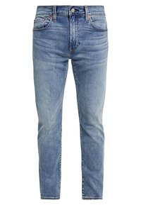 Jeans de color azul claro con un lavado desgastado, diseño clásico de cinco bolsillos, cierre de botón metálico y costuras decorativas a lo largo de las costuras.