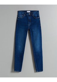 Tmavě modré džíny s úzkým střihem, pěti kapsami a standardním švem. Mírné vyblednutí na stehnech a zapínání na knoflík v pase.