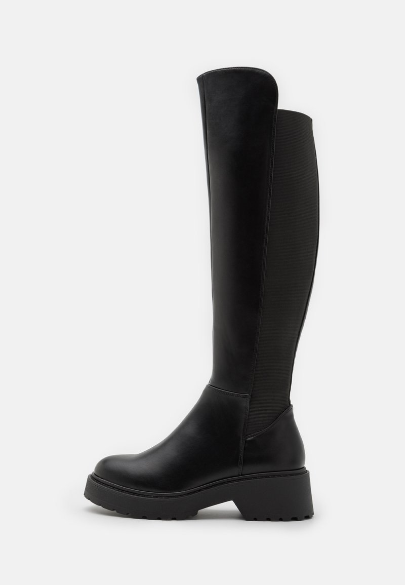 Bottes noires arrivant au genou avec un avant en cuir lisse et un panneau élastique à l'arrière. Semelle épaisse à plateforme avec un profil texturé.