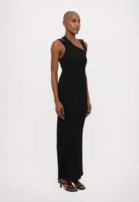 Black, fitted maxi dress with an asymmetrical neckline. Features slender straps and a side split, made from smooth, stretchy fabric.