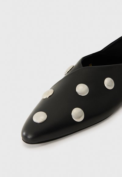 Chaussure en cuir noir à bout pointu, ornée de clous ronds en argent répartis de manière uniforme sur la surface supérieure. Texture lisse, design minimaliste.